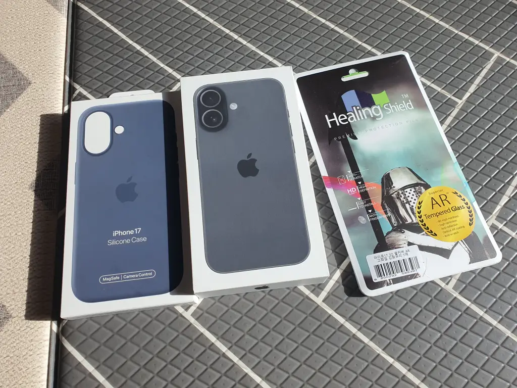 iPhone 17 unboxing photo showing the box, Apple iPhone 17 Silicone Case in blue, and Healing Shield AR tempered glass screen protector