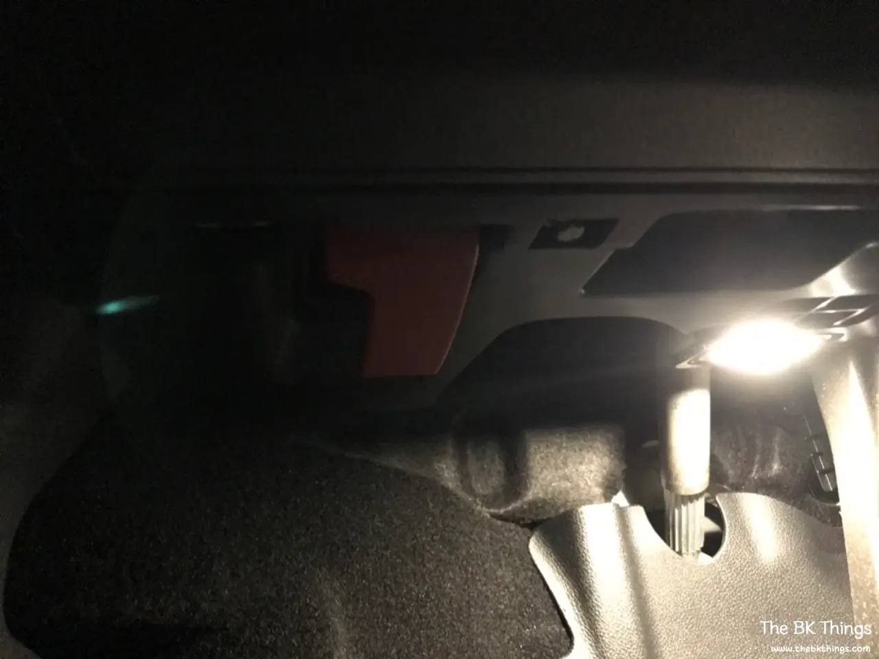 Driver footwell of a Mercedes A200 W176 showing where the OBD port is located near the red hood release lever